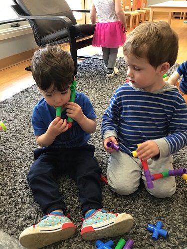 A toddler has created what looks like a snorkel with small tube blocks that fit together.