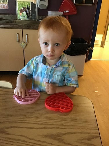 Toddler plays with a pop-it toy
