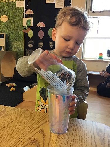 Toddler dumps straws into cup