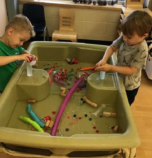 2 preschool boys using loose parts and tubes 