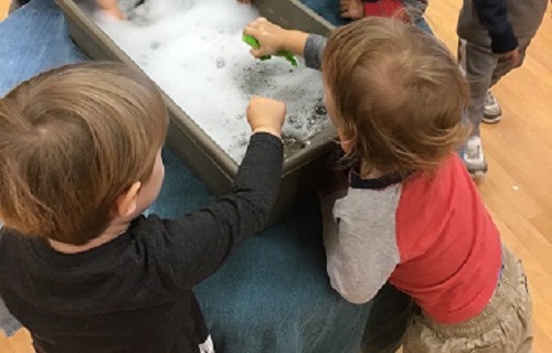 2 toddlers playing in the bubbles
