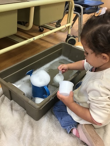 Toddler girl scooping water 