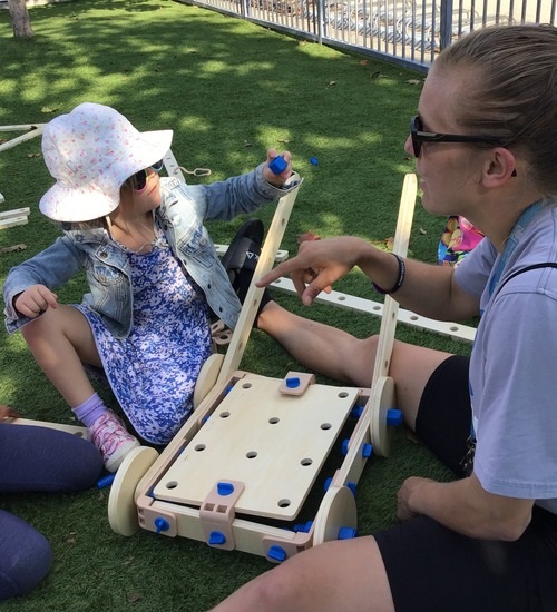 child working with educator to build mower