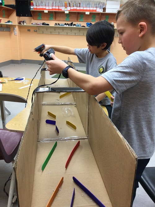 two children working to create their marble run