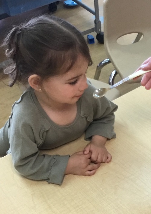 child smelling cinnamon on a teaspoon