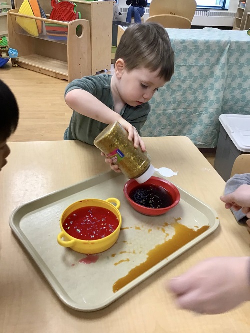 Child dumping glitter into water and ice