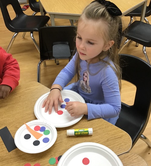 child making a snowman using paper plates