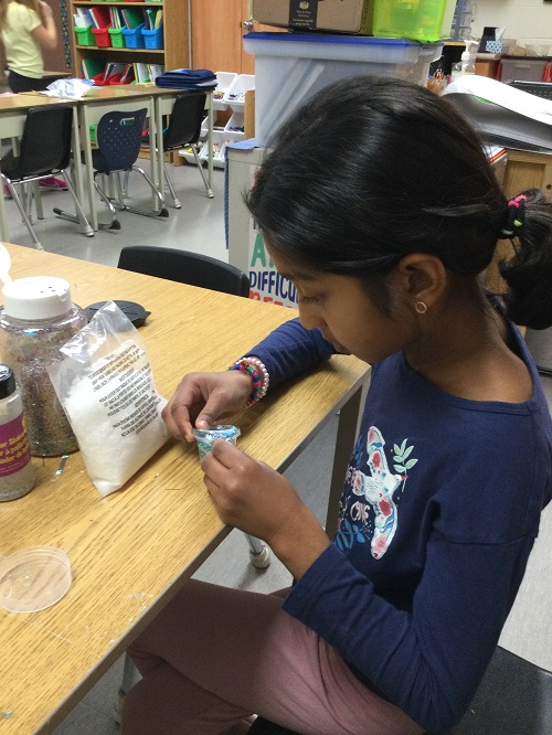 child gluing onto their ornament