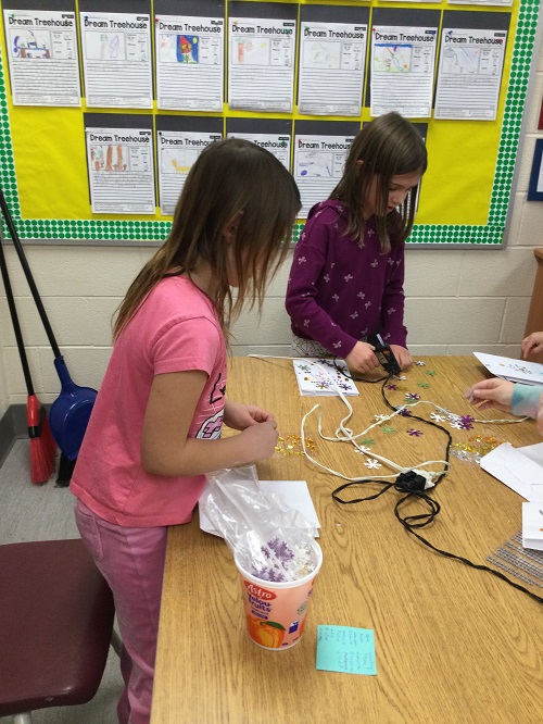 child using hot glue gun at a table