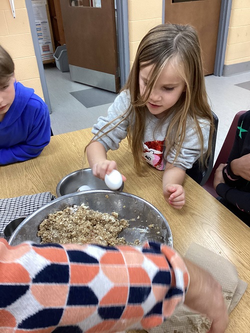childing breaking an egg into the mixture