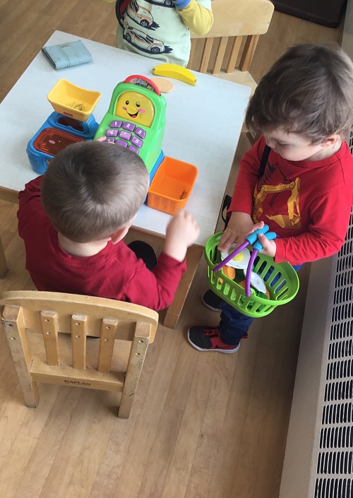 two children engaging with play market food at a table