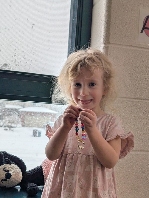 Child holding up their finished beaded creation