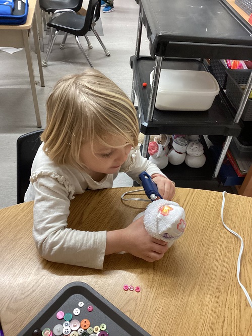 child gluing their snow person together