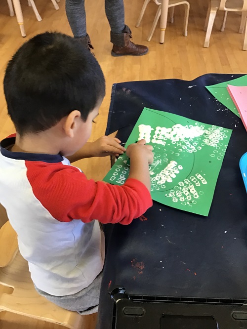 Preschool child making prints with paint on paper