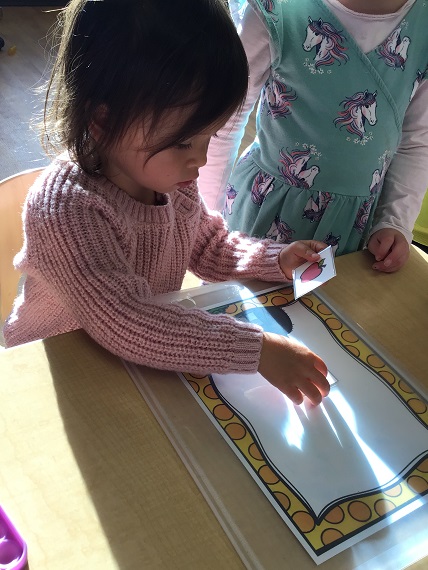 Preschool child placing counters on laminate photo frame