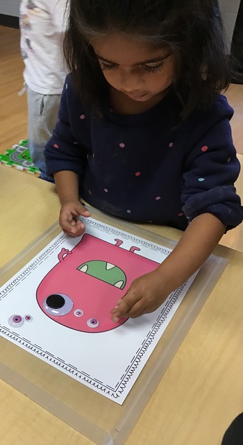 Preschool child placing counters on a photo of a monster