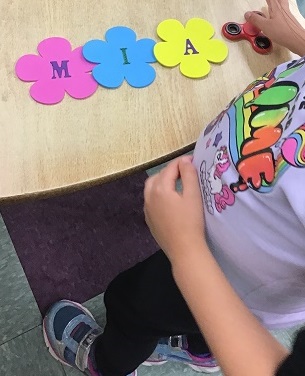 School age child spelling the name Mia out of flower letters
