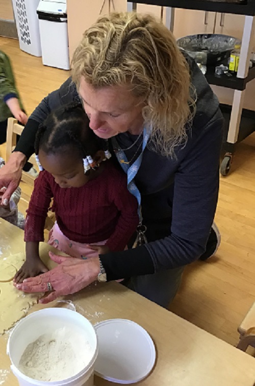 Child cutting a shape out of dough with educator.