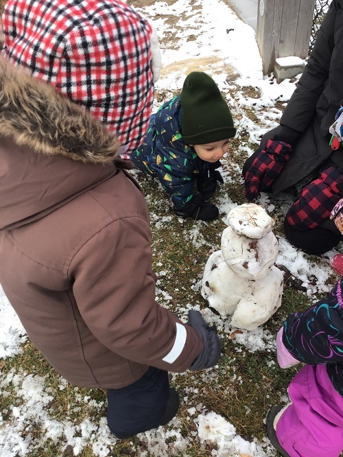 Children observing their created snowman. 