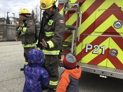 Chidren giving a high five to a fire fighter. 