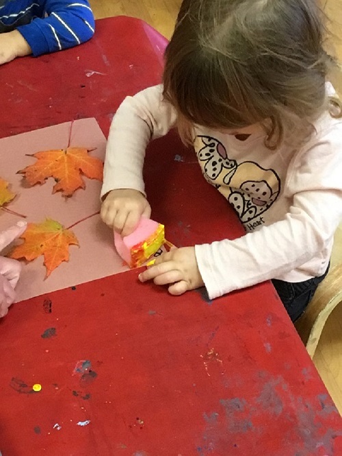 Child painting a fall leaf. 