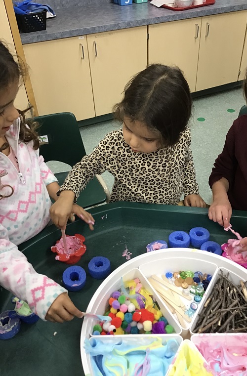 Children engaged in shaving cream and loose parts play.