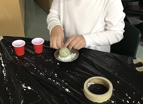 Child manipulating corn starch and soapy mixture.
