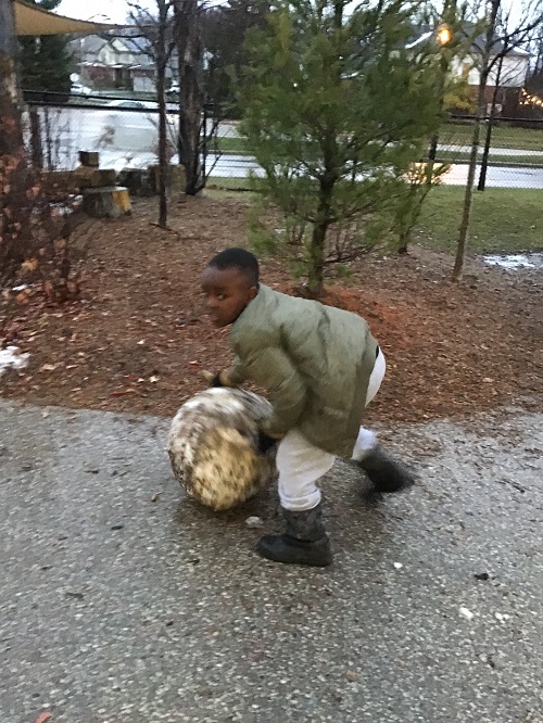 Child rolling a big snowball.
