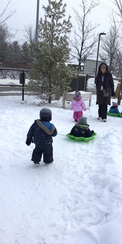 Educator pulling child on a sled.