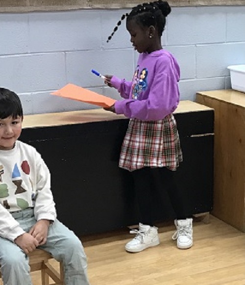 Child writing names on a piece of paper to keep score.