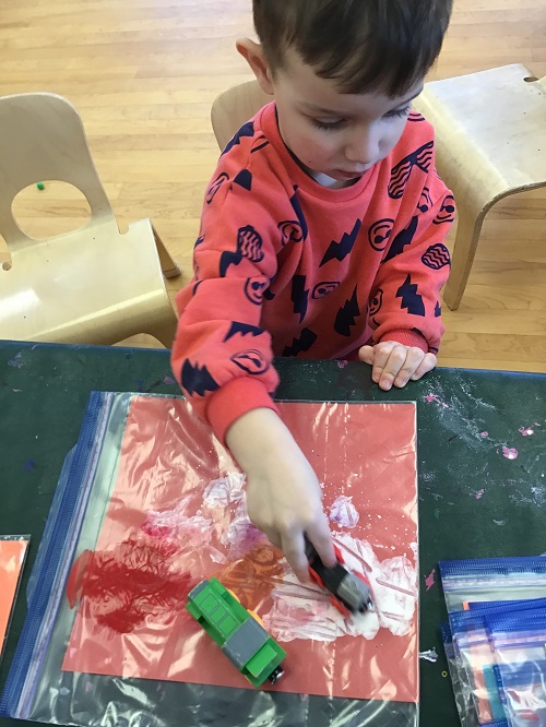 Child driving a car on top of the Ziplock bag filled with paint.