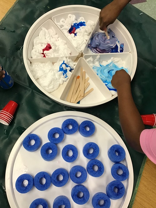 Children explering pool noodles, shaving cream and loose parts.