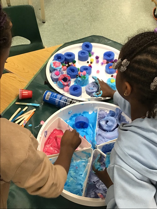 Children creating with shaving cream and loose parts.