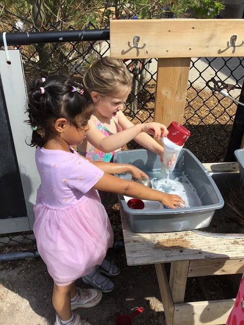 Child sharing space at a bin with a peer.
