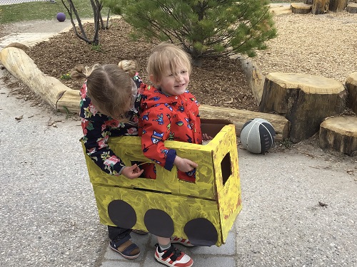 Children "driving" their cardboard school bus.
