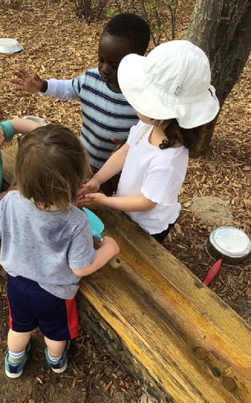 Children waiting to push the button on the water feature.