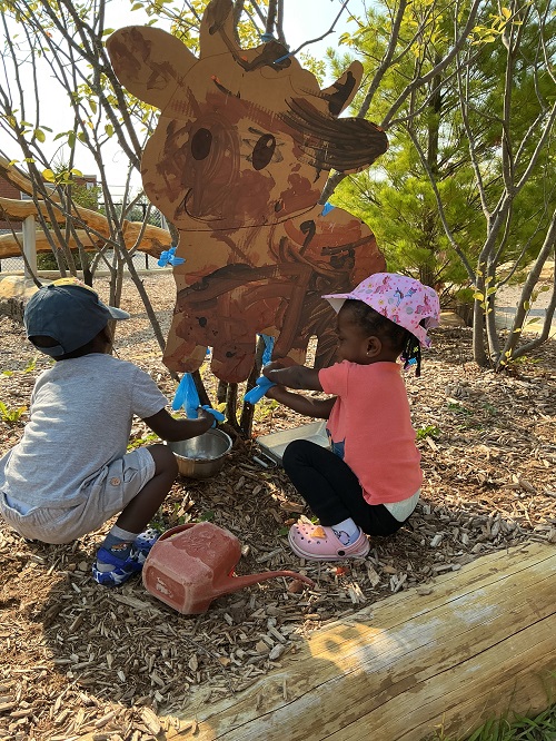 Children pretending to milk a cow.