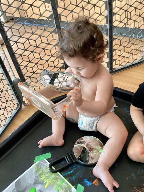 An infant looking at themselves in a mirror