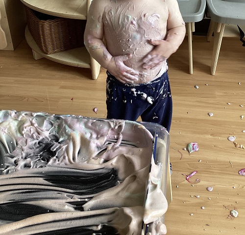 A child with chickpea foam all over their body from exploration