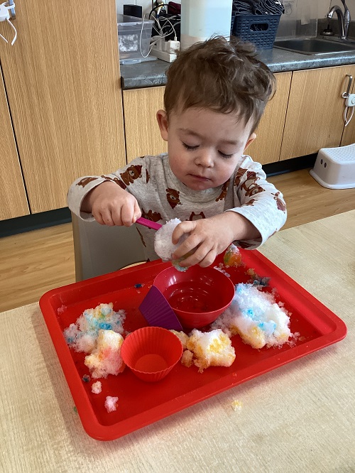 A child exploring with colours and snow.