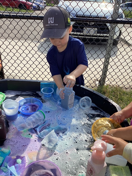 Children exploring foam with different items.