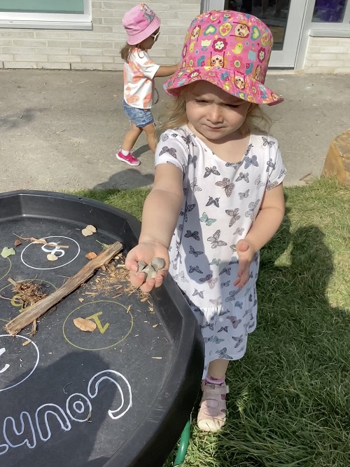 A child holding up a natural item they found on the playground.