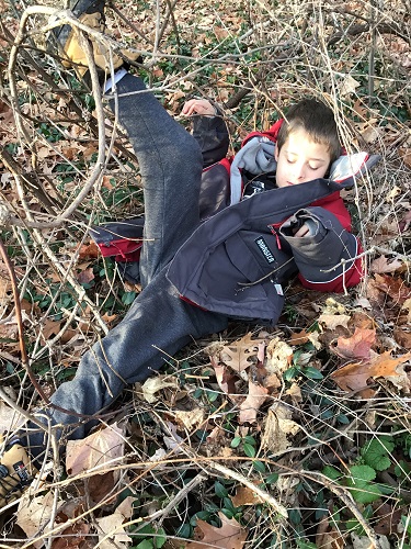 child laying in sticks and brush relaxing