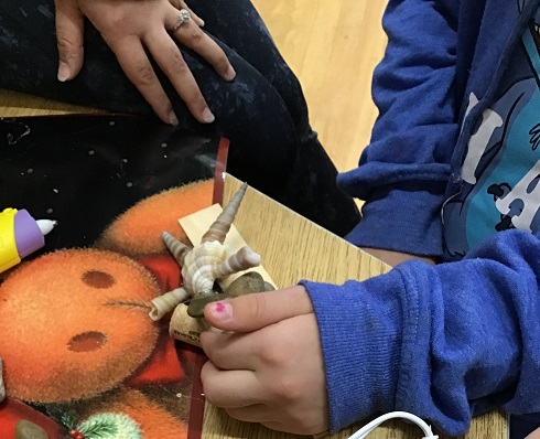 staff engaged with child while they show them their creation