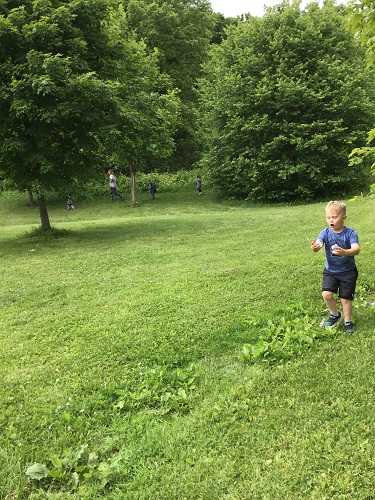 school age child on a grass hill seaching for a clear plastic orb 