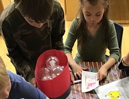 children at a table creatine images on Paper of pokemon creatures and looking at the pokemon they had caught 