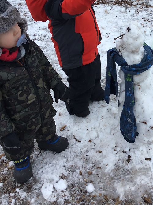 Toddlers admiring their snowman