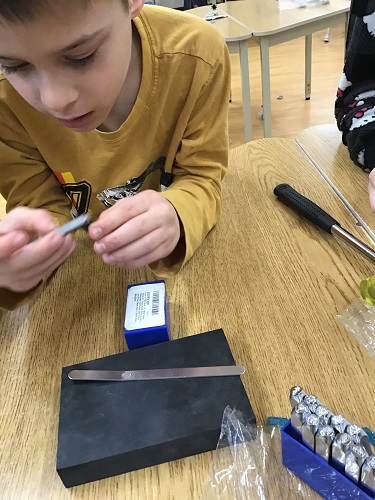 Child choosing metal piece to emboss shapes on bracelet