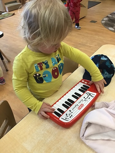 toddler child using a small electronic key board to make sounds 