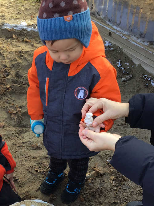 toddler child holding a ball of snow outside